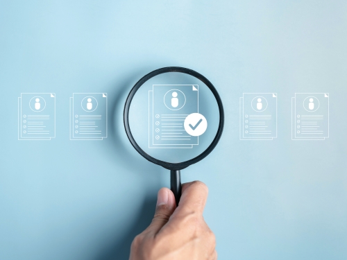 複数名の中から特定の個人のデータを虫眼鏡でよく見ているイメージ