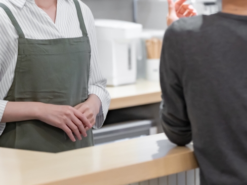 カフェのカウンターで顧客から注意を受ける店員